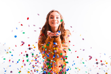 Obraz na płótnie Canvas Cute teen girl on a light background throws color candy. Party concept.