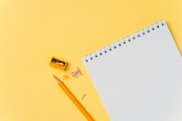 Empty notebook and pencil on bright yellow background