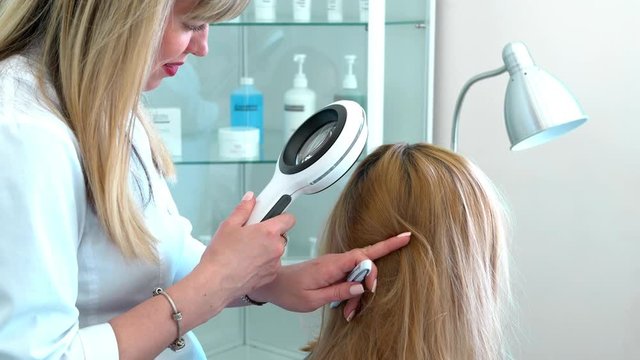 a professional doctor trichologist diagnoses the patient&rsquo;s hair and scalp. Clinic of cosmetology and dermatology. The concept of preventing diseases and hair loss