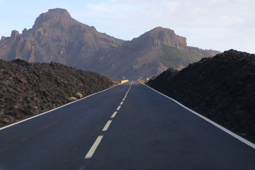 The road with blur in the foreground while driving and mountains with a volcano in the background