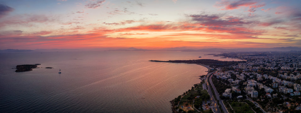 Panoramic aerial view of the Athens Riviera coast with beaches and restaurants during sunset time, Greece