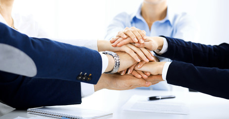Business team showing unity with their hands together. Group of people joining hands and representing concept of friendship, teamwork and partnership