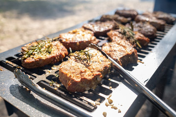 Grilling pork meat with barbecue stuff. Horizontal close up shot with a selective focus