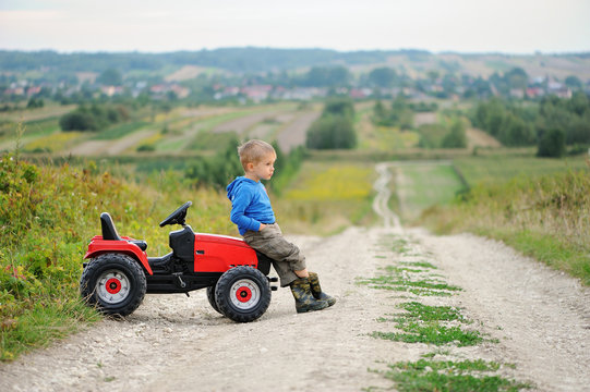 Child with a toy tractor on a trip.