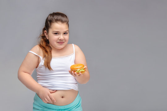  healthy eating, glutton, bad nutritional habits, overeating, fast food, overweight. baby girl with excess weight keeps the stomach. copyspace