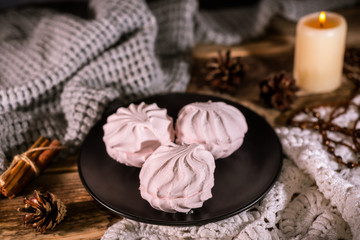 Homemade organic zephyr with candle and cinnamon sticks on rustic background. Pink marshmallow.
