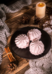 Homemade organic zephyr with candle and cinnamon sticks on rustic background. Pink marshmallow.