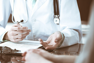 Doctor and  female patient sitting at the desk and talking  in clinic near window. Medicine and health care concept. Green is main color