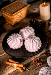 Homemade organic zephyr with candle and cinnamon sticks on rustic background. Pink marshmallow.