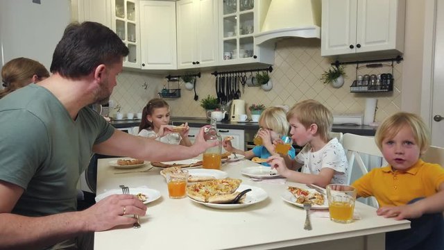 Family with children eating pizza at the table