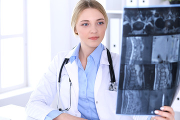 Doctor woman examining x-ray picture near window in hospital. Surgeon or orthopedist at work....