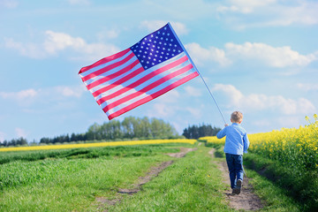 Happy child with the flag of the United States of America, back view, whole body, outdoor.