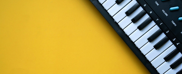 close up top view electric keyboard music instrument on yellow background concept