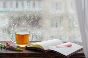 cup of tea on  background of  window with raindrops at sunset