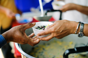 the concept of social inequality : Donating food to beggars to alleviate hunger : The hands of the poor receive food from the hands of the humane