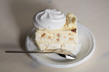 Piece of cake with meringue and nuts on a wooden table