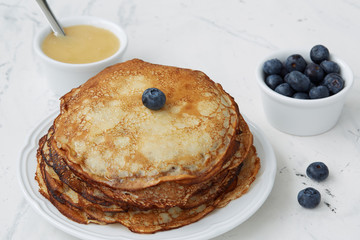 Homemade pancakes with blueberries and honey on a light background