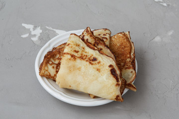 Homemade pancakes served on plate, crepes on grey concrete background