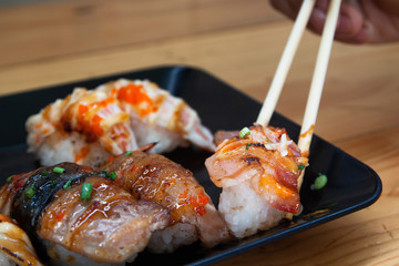 Close up fresh homemade sushi with chopsticks on plate.