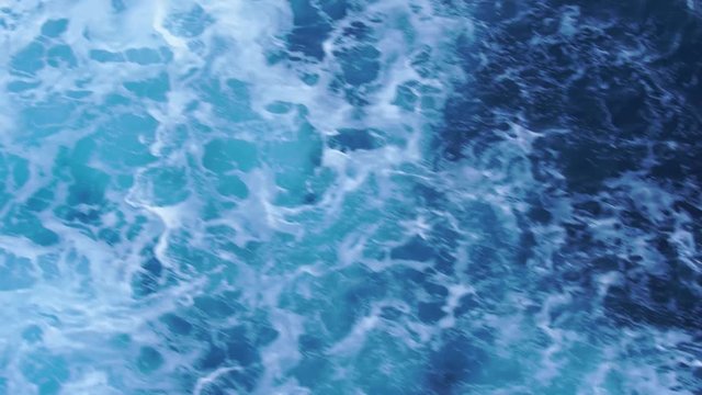 Waves with foam behind a boat. Patterns of waves in water. Water surface wake view from the cruise liner in 4k