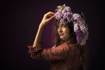 Portrait of attractive young woman with long curly hair and wreath on a head.