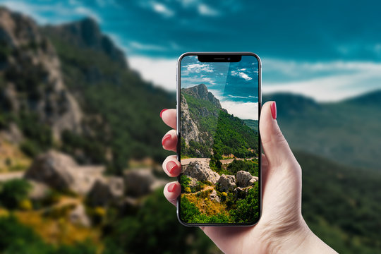 Girl photographs the landscape on the smartphone. Travel concept.