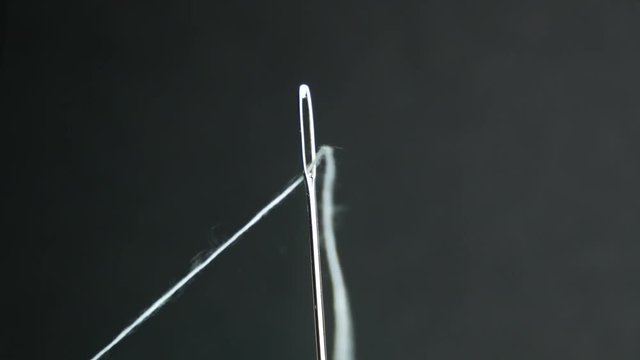 Close up needle with white thread, preparation for sewing. Stop motion
