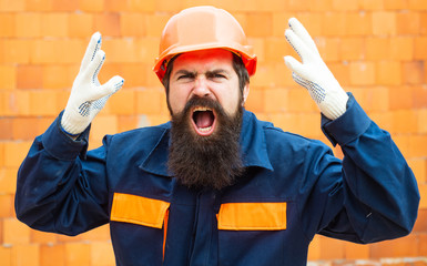 Angry builder. Incident at a construction site. Safety rules for builders. Bearded man in helmet on...