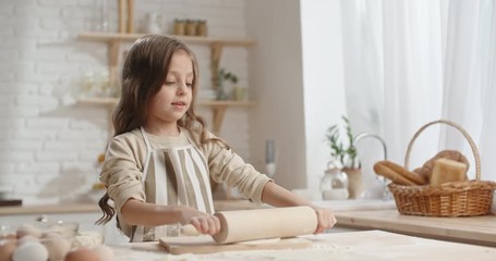 Cute caucasian girl is learning how to cook, preparing dough for cookies, dreaming of becoming a chef - childhood dream, childhood memories concept 4k