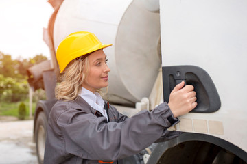 Woman concrete truck driver with helmet enters the truck