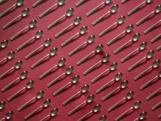 Silver small spoons patter on red background