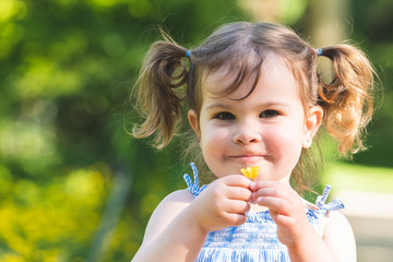 Little Girl Holding a Flower Outdoors.