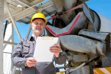 Civil engineer wearing hardhat  checking schedule on ready mix concrete plan