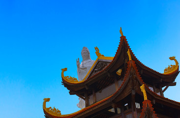 Fototapeta premium CloseUp of Ho Quoc Pagoda and big white Buddha statue on the blue sky. The biggest ancient Buddhist temple in Phu Quoc Island, Vietnam. Religion and travel concept.