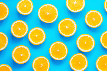 Fresh orange slices patterned over blue background, top view
