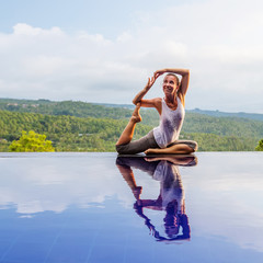 Caucasian woman practicing yoga by the pool