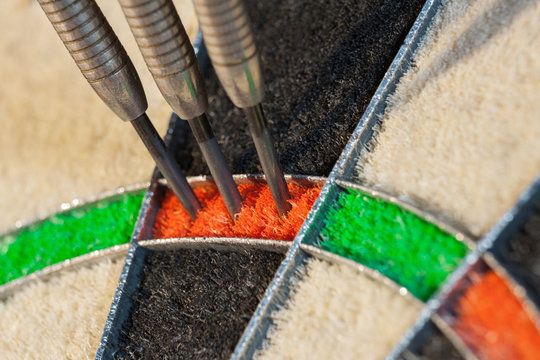 Close up view on three darts in triple twenty sector of sisal dartboard