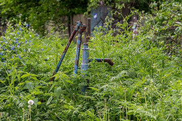 Vintage rusty water fountain hand pump in russian village. Abandoned water wellhead.