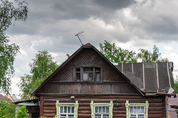 Old house in a Russian village against a cloudy sky, gray clouds.