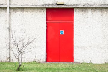 Fire exit red door and white wall at work place