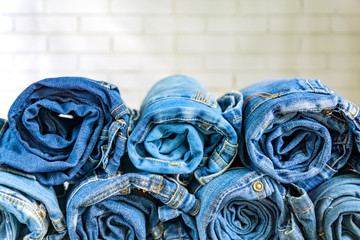 roll blue denim jeans arranged in stack on wall background. Beauty and fashion clothing concept