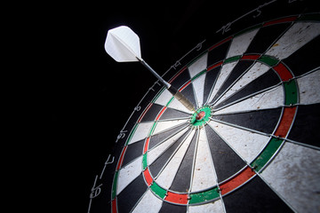 darts board on a black background. 1 dart in the center