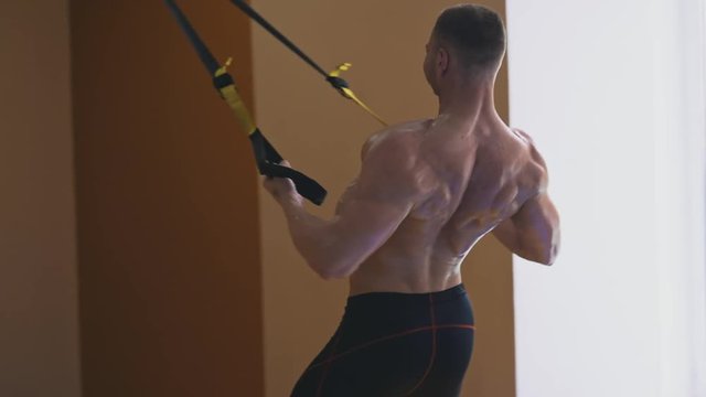 Strong man training with trx in a fitness club