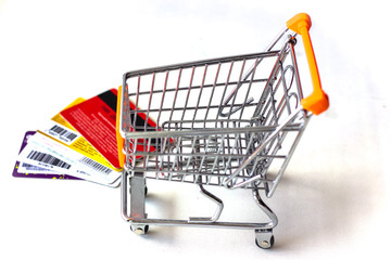 Shopping cart with credit cards and money on white isolated background