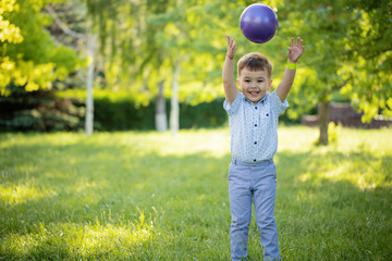 Sporty cute positive kid, playing happily with big ball on green meadow.little boy play in green grass