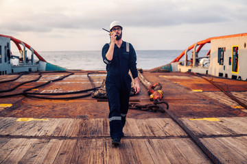 Deck Officer on deck of offshore vessel or ship , wearing PPE personal protective equipment. He...