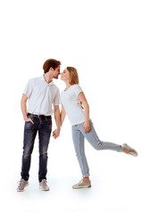 Beautiful young couple in casual clothing flirting, white background