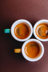 Threee colorfull cups of espresso coffee on dark background