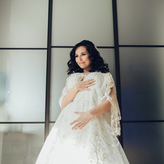 Bride in white luxury dress is getting ready for wedding. Morning preparations. Woman putting on...