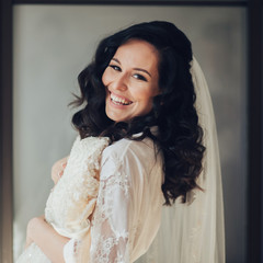 Bride in white luxury dress is getting ready for wedding. Morning preparations. Woman putting on dress.